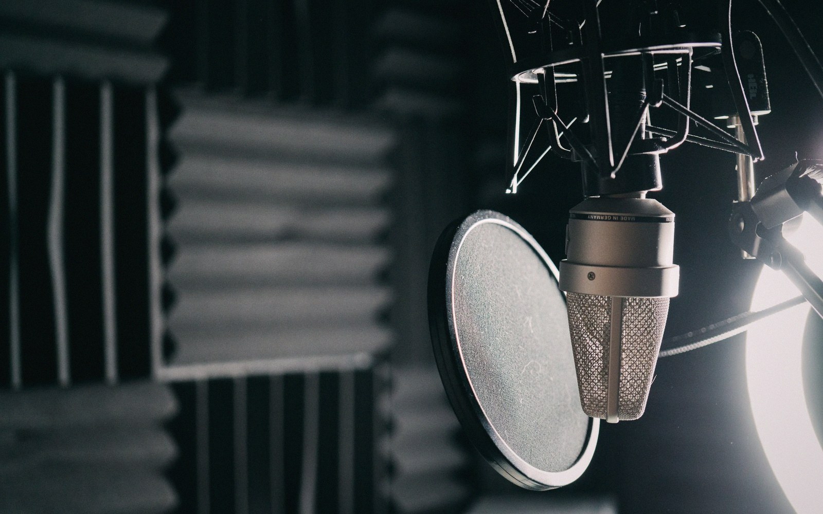 A narration booth with foam walls, a music stand and a microphone, empty